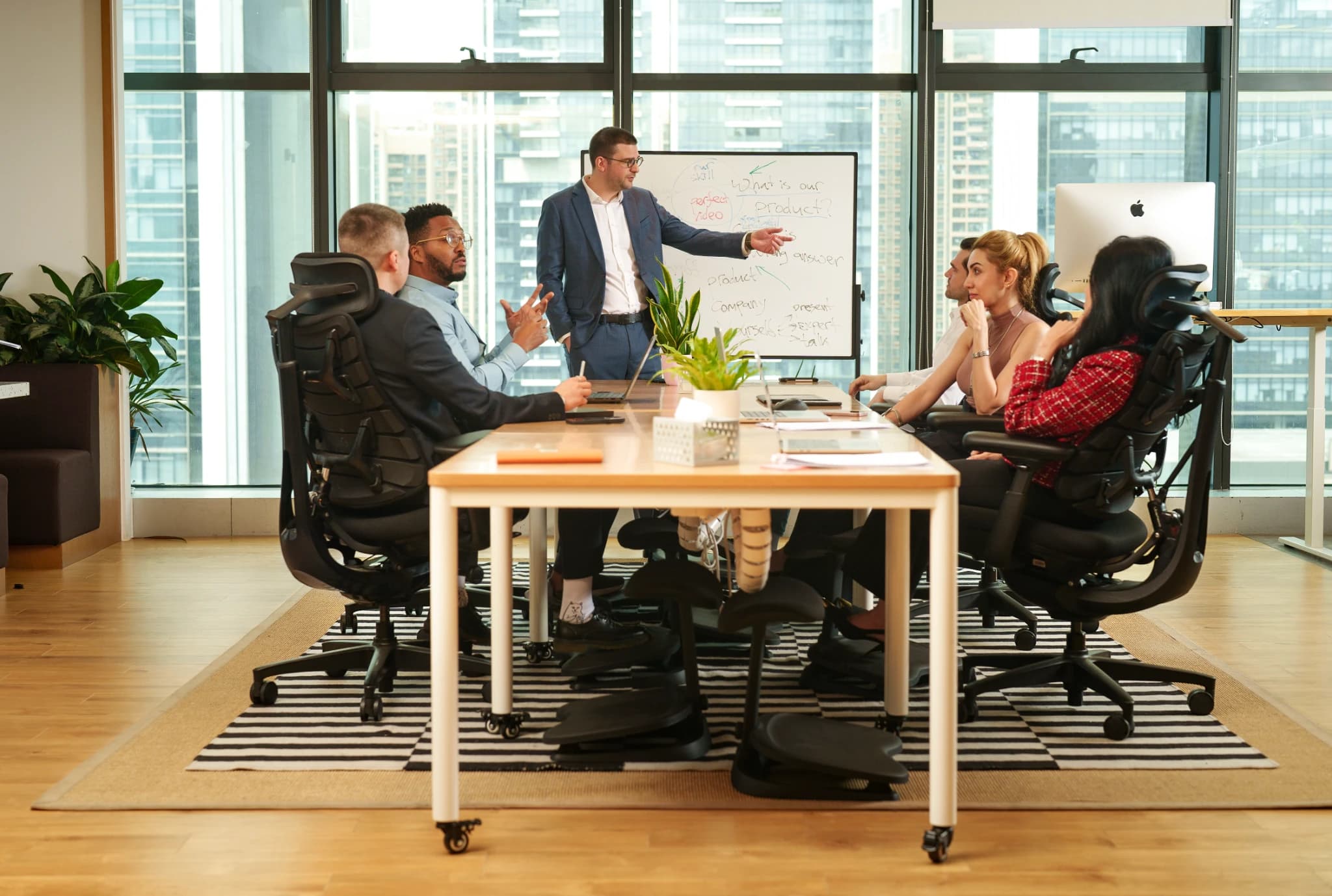 Business team collaborating around a meeting table while seated in ergonomic office chairs